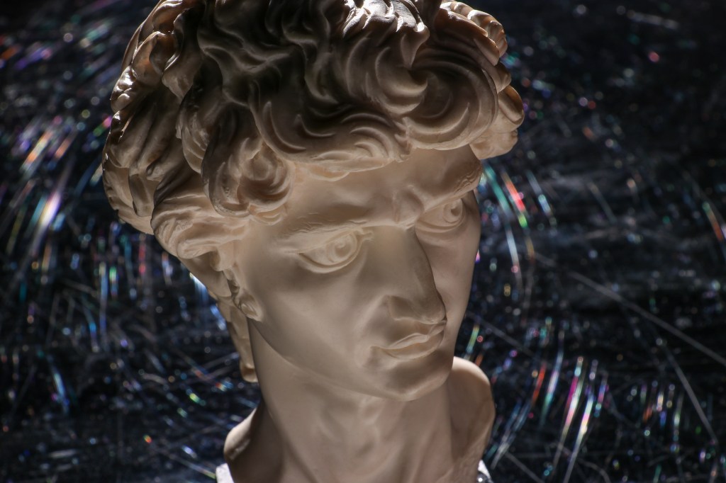 White stone bust of David by Michelangelo on a prismatic black background