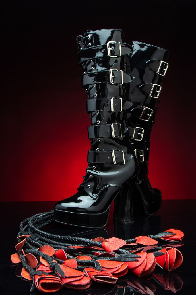 Fetish boots with a nine-tailed cat o'nine tail leather whip with leather red rosebud ends