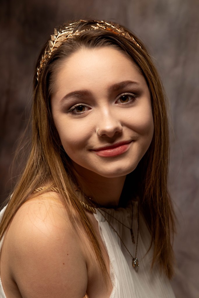 Fairskinned woman with straight golden brown hair wearing white